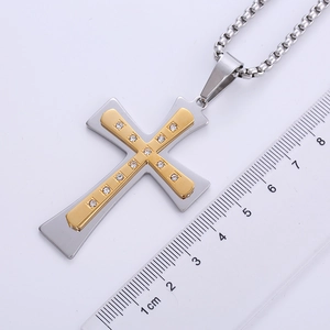 Two-tone stainless steel cross pendant with crystals shown next to a measuring ruler