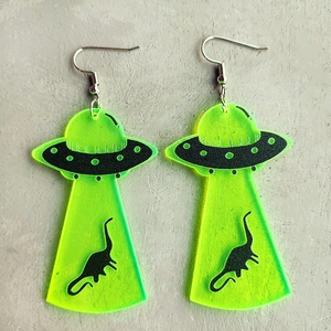 Detail of neon green acrylic UFO and dinosaur earrings for Halloween festival