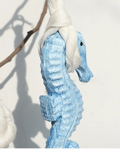 Detail of blue seahorse wall decor with distressed texture and cotton rope hanger
