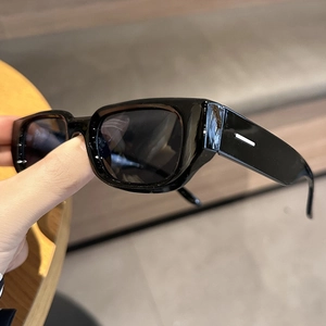 Close-up of retro irregular black sunglasses featuring wide temples and white accents