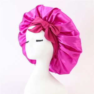 Detail of magenta satin sleep cap featuring a large decorative bow and smooth texture