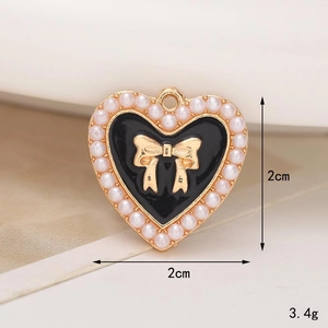 Macro shot of heart charm with black enamel, gold bow, and pearls for shoe charms