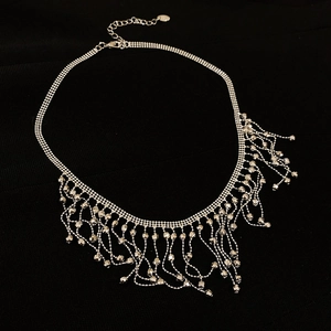 Detailed view of silver tassel necklace with lobster clasp and extension chain on black background