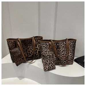 Detail shot of leopard print tote bag set featuring brown leather handles and small pouch