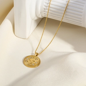 Close-up of 18K gold plated coin pendant with snake engraving and white zircon inlay