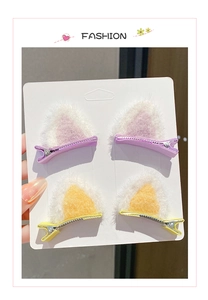 Close-up of four plush cat ear hair clips in purple and yellow on a display card
