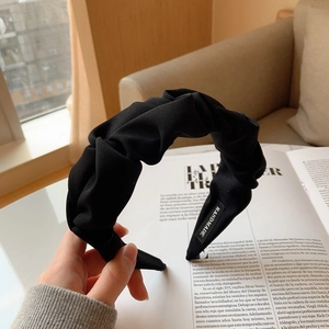 Détail d'un serre-tête plissé noir fait main avec étiquette tissée à l'intérieur