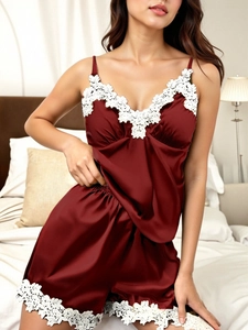 Close-up of elegant burgundy satin pajamas with white lace trim and floral embroidery
