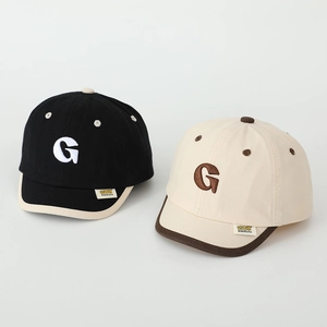 Close-up of kids baseball caps featuring embroidered letter G and fabric label detail