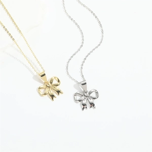 Minimalist bow pendant necklace in gold and silver finishes on a white background