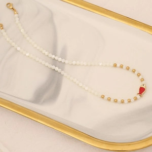 Detailed shot of fish pendant beaded necklace on a white marble tray with gold trim