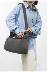 Detail of dark grey nylon padded shoulder bag with knotted strap and puffy texture