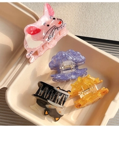 Top view of a set of four colorful acetate hair claws with cute animal and cloud shapes