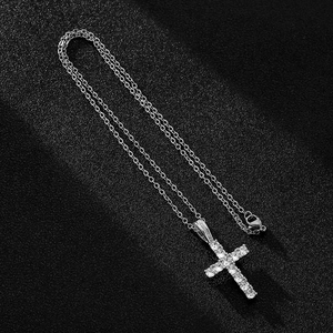 Macro shot of silver cross pendant with sparkling zircons on a textured black background