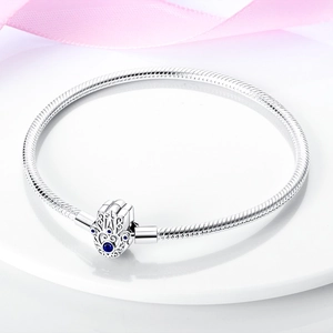 Silver Hamsa Hand snake chain bracelet with blue gemstone on an elegant white pedestal