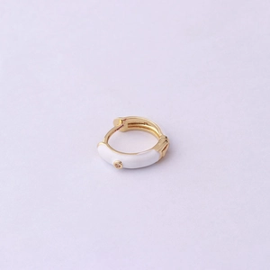 Detail of gold huggie hoop earring with white enamel and tiny sparkling crystal accent
