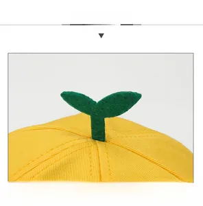 Gros plan d'une casquette en coton jaune avec une petite pousse verte sur le dessus