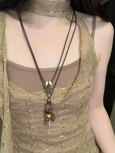 Detail of bohemian leather necklace with star and feather pendants on lace top