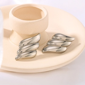 French vintage silver angel wing earrings with layered wave design on ceramic tray