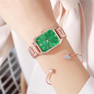 Close-up of rectangular green watch face with rose gold band and heart bracelet