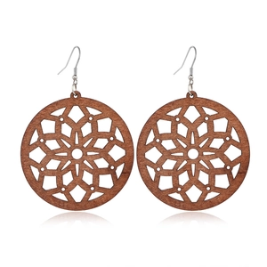 Detail view of round wooden earrings featuring intricate hollowed geometric patterns
