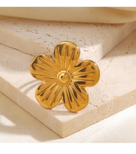 Vue détaillée d'une bague fleur plaquée or 18K sur travertin beige et soie blanche