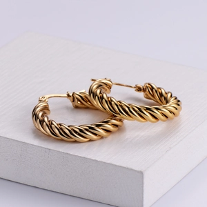 Detailed view of gold twisted hoop earrings with a shiny metallic rope texture on display