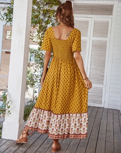 Detail of bohemian yellow floral maxi dress with elastic smocked back and ruffled hemline