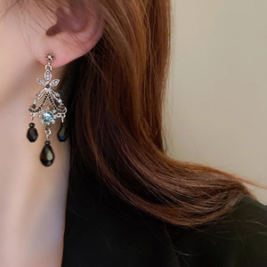 Detail of vintage palace style earrings with blue rhinestones and black teardrop beads