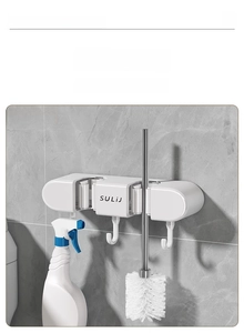 Detail view of wall-mounted suction mop holder with hooks holding tools on marble tile
