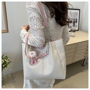Borsa tote bianca con manici rosa e ciondolo di peluche indossata da una modella