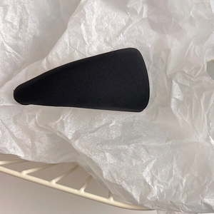 Macro shot of a black fabric triangle hair clip on textured paper in a mesh basket