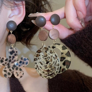 Detailed macro view of leopard print resin flower and layered ring dangle earrings