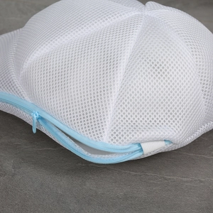 Detailed close-up of durable polyester mesh fabric and light blue zipper on laundry bag