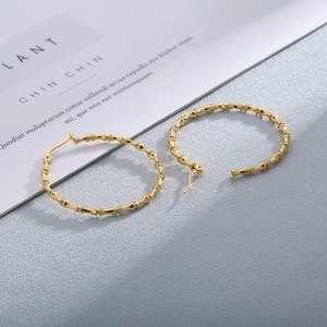 Detail view of golden bamboo pattern hoop earrings with secure clasp mechanism