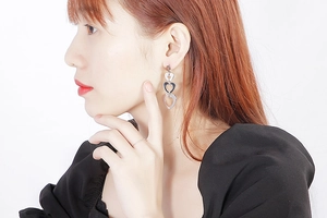 Gros plan de boucles d'oreilles pendantes à trois cœurs argentés portées par un mannequin