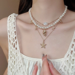 Close-up of layered necklace with starfish, conch shell pendants and baroque pearl details
