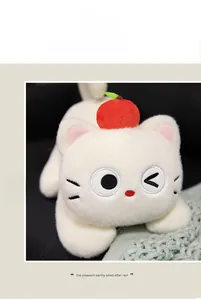 Detail of white plush cat with red apple hat and embroidered winking face