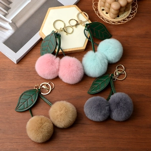 Detail of colorful cherry-shaped faux rabbit fur pompom keychains on dark wood