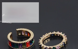 Macro shot of colorful zircon stones set in gold adjustable rings on dark background