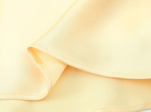 Détails de la texture du tissu en satin jaune clair brillant et du drapé de qualité
