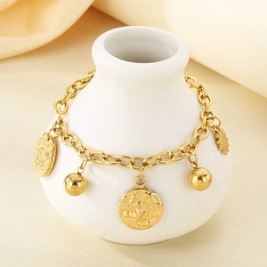 Golden chunky chain bracelet with sun coin pendant and polished sphere on ceramic decor
