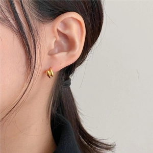 Close-up of minimalist irregular gold twist earrings on model with molten metal texture