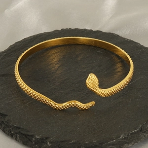 Bracelet jonc serpent doré élégant avec texture d'écailles sur fond de pierre noire