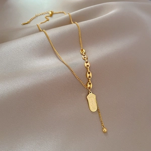 Macro shot of 18k gold plated titanium steel Y-necklace on beige satin background
