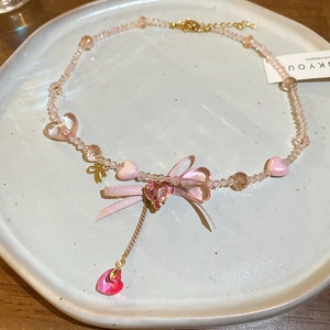 Detail of pink beaded necklace with bow and heart pendant on ceramic plate
