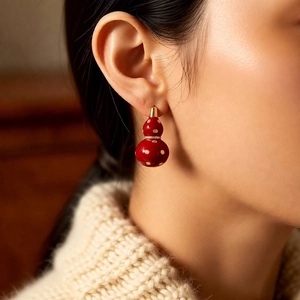 Detail of red gourd earring with gold dots and micro-inlay zircon on a female model