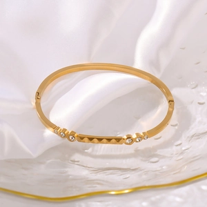 Golden geometric circle bangle with sparkling zircons on a white silk background