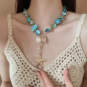 Close-up of ocean-style necklace with turquoise beads, golden starfish and seashells