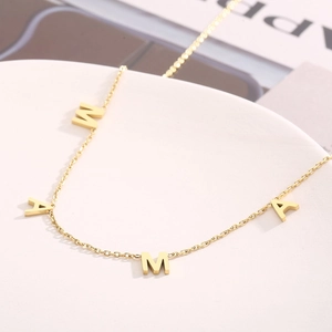 Détail du pendentif lettre MAMA doré sur une chaîne de collier en acier inoxydable
